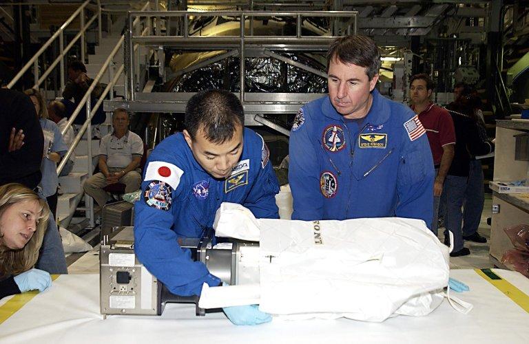 KENNEDY SPACE CENTER, FLA. -- STS-114 Mission Specialist Soichi Noguchi, with the National Space Development Agency of Japan (NASDA), works with equipment as Mission Specialist Stephen K. Robinson, Ph.D., (right) watches. The STS-114 crew is participating in familiarization activities with the hardware that will fly on the mission. STS-114 is a utilization and logistics flight (ULF-1) that will carry Multi-Purpose Logistics Module Raffaello and the External Stowage Platform (ESP-2), as well as the Expedition 7 crew, to the International Space Station. Launch is targeted for March 1, 2003.