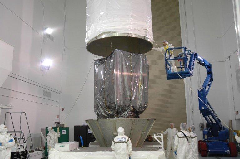 KENNEDY SPACE CENTER, FLA. -- At Astrotech Space Operations in Titusville, Fla., workers guide the upper transportation canister as it is lowered onto the Dawn spacecraft. The canister will be attached to the bottom segments already in place. The canister will protect the spacecraft and booster during transfer to Launch Pad 17-B at Cape Canaveral Air Force Station (CCAFS). During its nearly decade-long mission, the Dawn mission will study the asteroid Vesta and dwarf planet Ceres, celestial bodies believed to have accreted early in the history of the solar system. To carry out its scientific mission, the Dawn spacecraft will carry a visible camera, a visible and infrared mapping spectrometer, and a gamma ray and neutron spectrometer, whose data will be used in combination to characterize these bodies. In addition to the three instruments, radiometric and optical navigation data will provide data relating to the gravity field and thus bulk properties and internal structure of the two bodies. Data returned from the Dawn spacecraft could provide opportunities for significant breakthroughs in our knowledge of how the solar system formed. Launch via a Delta II rocket is scheduled in a window from 7:25 to 7:54 a.m. Sept. 26 from CCAFS. Photo credit: NASA/Jim Grossmann