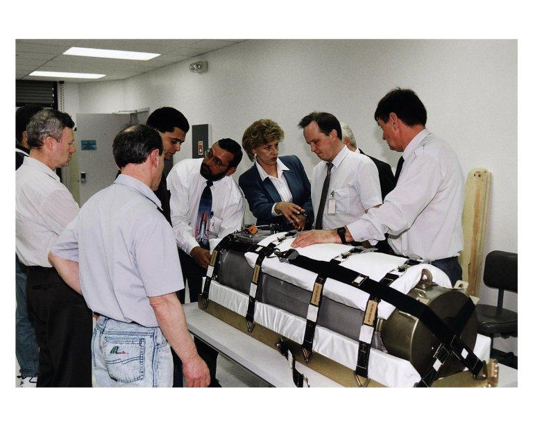 Representatives of RSC Energia in Russia and other onlookers in the SPACEHAB Payload Processing Facility examine an oxygen generator which the Space Shuttle Atlantis will carry to the Russian Mir Space Station on Mission STS-84. Sergei Romanov, second from right in the white shirt, is the spokesperson for generator manufacturer RSC Energia. The nearly 300-pound generator will be strapped down on the inside surface of a SPACEHAB Double Module for the trip to Mir. It will replace one of two Mir units that have been malfunctioning recently. The generator functions by electrolysis, which separates water into its oxygen and hydrogen components. The hydrogen is vented and the oxygen is used for breathing by the Mir crew. The generator is 4.2 feet in length and 1.4 feet in diameter. STS-84, which is planned to include a Mir crew exchange of astronaut C. Michael Foale for Jerry M. Linenger, is targeted for a May 15 liftoff. It will be the sixth Shuttle-Mir docking