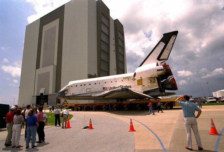 While KSC workers in the Launch Complex 39 Area watch, The Space Shuttle Orbiter Columbia rolls over to the Vehicle Assembly Building (VAB) June 4 from Orbiter Processing Facility (OPF)1 atop its transporter in preparation for the STS-94 mission. Once inside the VAB, Columbia will be hoisted to be mated with its solid rocket boosters and external tank. Columbia was moved to the OPF April 8 after the completion of the STS-83 mission. KSC payloads processing employees then began work to reservice the Microgravity Science Laboratory-1 (MSL-1) Spacelab module in the orbiter?s payload bay for the STS-94 mission. This was the first time that this type of payload was reserviced without removing it from the payload bay. This new procedure pioneers processing efforts for possible quick relaunch turnaround times for future payloads. The MSL-1 module will fly again with the full complement of STS-83 experiments after that mission was cut short due to indications of a faulty fuel cell. During the scheduled 16-day STS-94 mission, the experiments will be used to test some of the hardware, facilities and procedures that are planned for use on the International Space Station while the flight crew conducts combustion, protein crystal growth and materials processing experiments