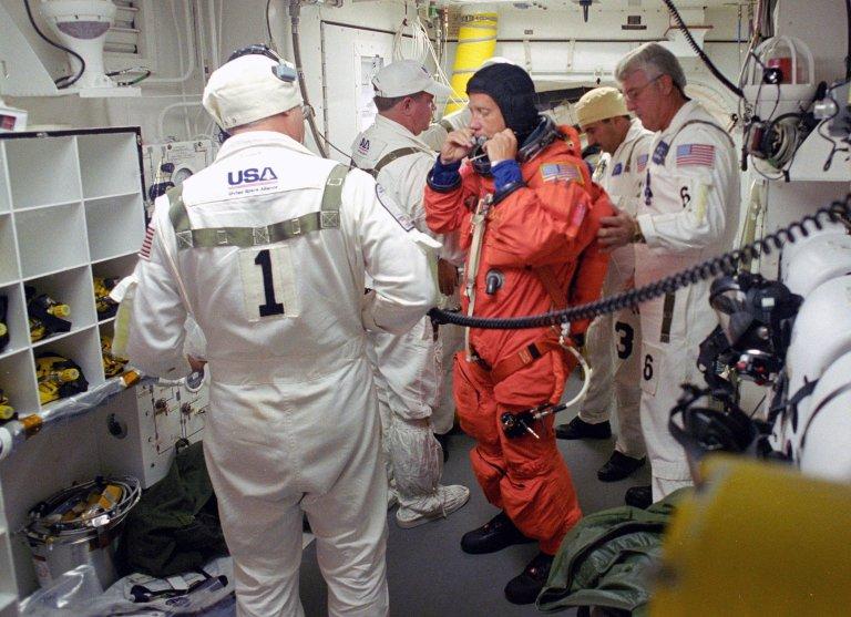 KENNEDY SPACE CENTER, FLA. - In the White Room on Launch Pad 39B, STS-121 Commander Steven Lindsey is helped by the Closeout Crew to prepare his launch suit for entering Discovery and the launch. Situated on the end of the orbiter access arm, the White Room provides access into the orbiter on the pad. The crew is preparing for the third launch attempt in four days; previous attempts were scrubbed due to weather concerns. During the 12-day mission, the STS-121 crew will test new equipment and procedures to improve shuttle safety, as well as deliver supplies and make repairs to the International Space Station. The launch of Space Shuttle Discovery on mission STS-121 is the 115th shuttle flight and the 18th U.S. flight to the International Space Station. Photo credit: NASA/Regina Mitchell-Ryall & Tony Gray